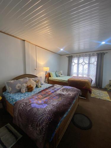 1 dormitorio con 2 camas con animales de peluche en Máple farmstay, en Darjeeling