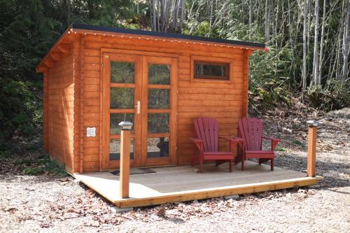 a small wooden cabin with two chairs and a table at The Elderberry Cabin - Cowichan Valley Bunkie Glamping in Duncan