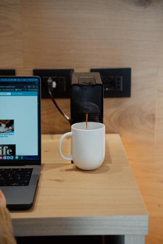 a coffee cup sitting on a table next to a laptop at Mostesi Dolomites Spa Hotel in Auronzo di Cadore