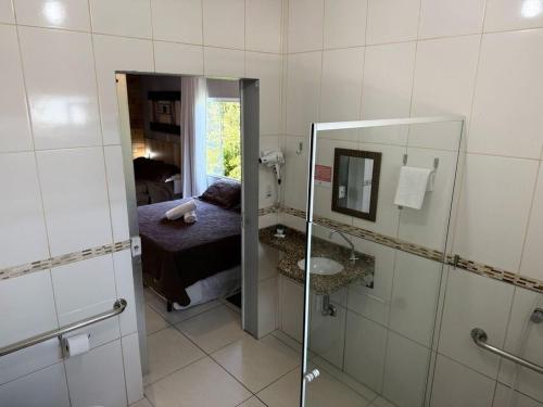 a bathroom with a mirror and a bed and a sink at Pousada Carolina Apartamentos in Penha