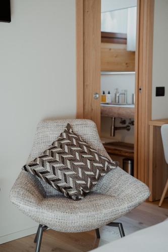 a chair with a pillow on it in a room at Mostesi Dolomites Spa Hotel in Auronzo di Cadore