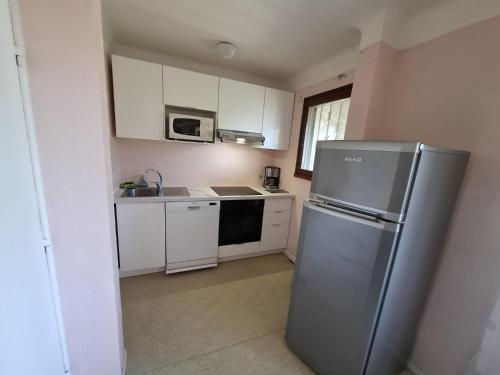 une cuisine avec un réfrigérateur en acier inoxydable et des armoires blanches dans l'établissement les campanules, à Saint-Aygulf