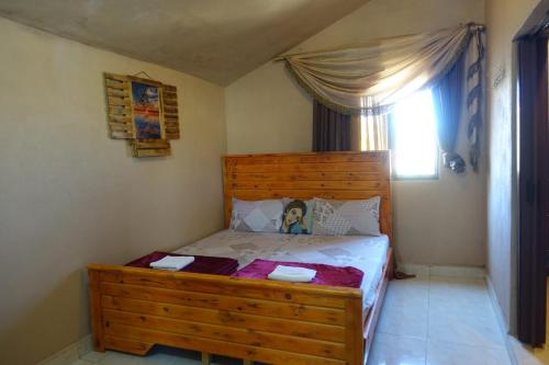 a bedroom with a wooden bed and a window at Dana bedouin Sky in Dana
