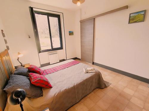 une chambre avec un lit avec des oreillers et une fenêtre dans l'établissement Le Sancy gîte Murol, à Murol