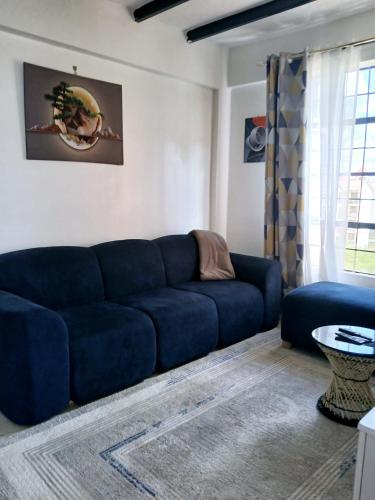 a living room with a blue couch and a table at Cozy Haven kitengela in Makandara