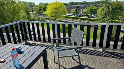 a wooden table and a chair on a balcony with a table and a drink at Cozy stay with beautiful balcony in Utrecht in IJsselstein