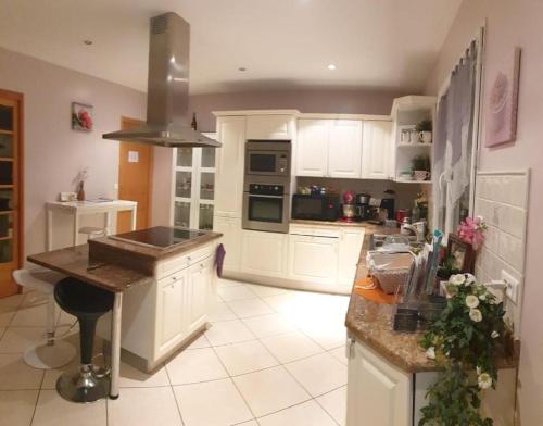 une cuisine avec des placards blancs et un îlot. dans l'établissement Grande suite salle de bain toilette privés prés Paris, à Corbeil-Essonnes