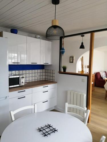 une cuisine avec des armoires blanches et une table et des chaises dans l'établissement La tidette, à La Celle-sous-Gouzon