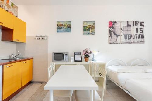 a living room with a white table and a kitchen at Beachfront Studio Free Parking-Pool 50m from Sea in Chioggia