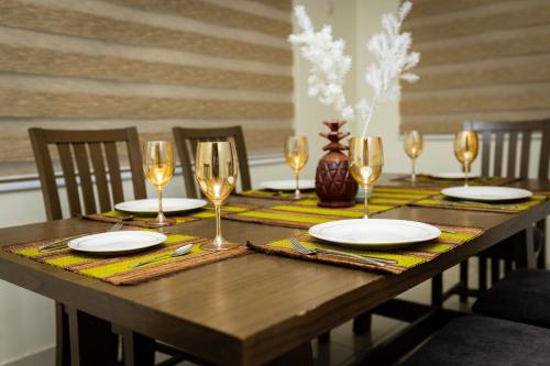 a wooden table with plates and wine glasses on it at Akwaaba Fie in Accra
