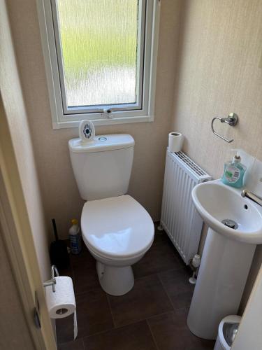 a bathroom with a toilet and a sink and a window at Ladram Bay, 2 Bedroom, Pet Friendly, Wi-Fi, Sleeps 6 in Otterton
