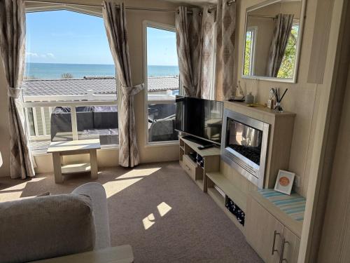 a living room with a television and a view of the ocean at Ladram Bay, 2 Bedroom, Pet Friendly, Wi-Fi, Sleeps 6 in Otterton