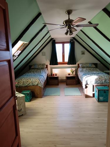 a attic room with two beds and a ceiling fan at Green Hilltop in Krušljevo Selo