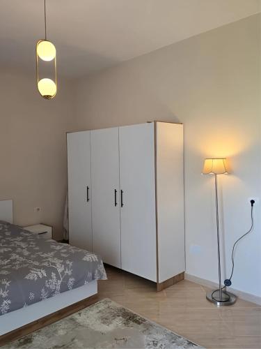 a bedroom with a white cabinet and a lamp at Prima Apartments in Pogradec
