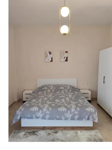 a white bedroom with a bed with a blue comforter at Prima Apartments in Pogradec