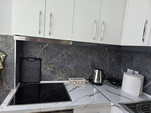 a kitchen with white cabinets and a stove top oven at Prima Apartments in Pogradec