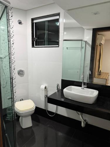 a bathroom with a toilet and a sink and a mirror at Casa em Guarapari in Guarapari