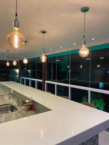 a kitchen with a counter with a sink and lights at Casa em Guarapari in Guarapari
