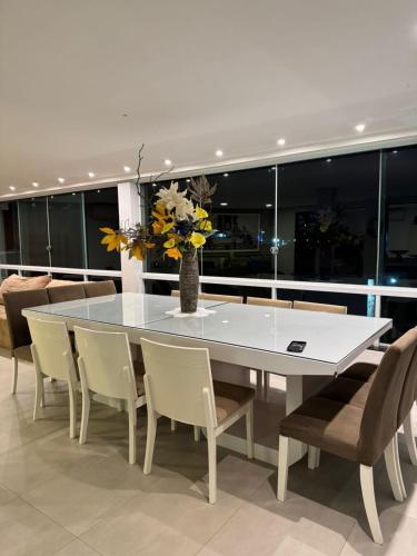 a dining room table with chairs and a vase with flowers at Casa em Guarapari in Guarapari