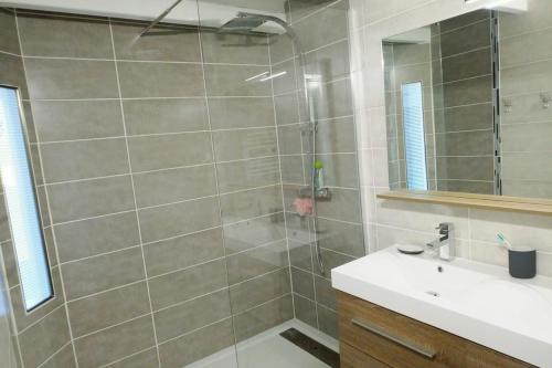 une salle de bain avec une douche avec un lavabo et un miroir dans l'établissement Appartement au cœur de La Rochelle avec parking, à La Rochelle