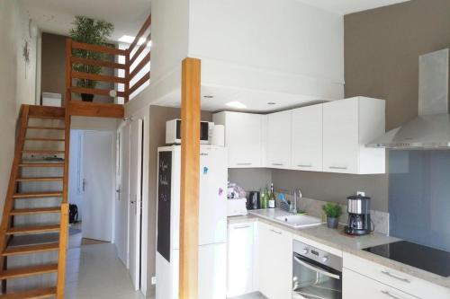 une cuisine avec des placards blancs et un escalier. dans l'établissement Appartement au cœur de La Rochelle avec parking, à La Rochelle