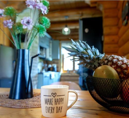 a coffee cup and a vase with flowers and a bowl of fruit at Holiday home Nola in Fužine