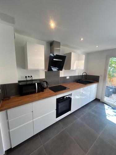 La cuisine est équipée de placards blancs et d'un four micro-ondes noir. dans l'établissement Maison 4 pers proche du centre, à Vaison-la-Romaine