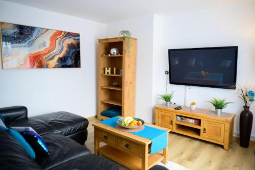 a living room with a black leather couch and a tv at Modern house , Perfect for business trip & Families holiday or working proffesionals-5 min from M1 J25 , 500MB Wi-Fi , Netflix , Fully equiped kitchen , Asda supermarket 5 min walk , Free Secure parking with CCTV ,available monthly deals in Nottingham