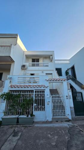 a white house with a gate in front of it at Calasetta, casa vista mare in Calasetta