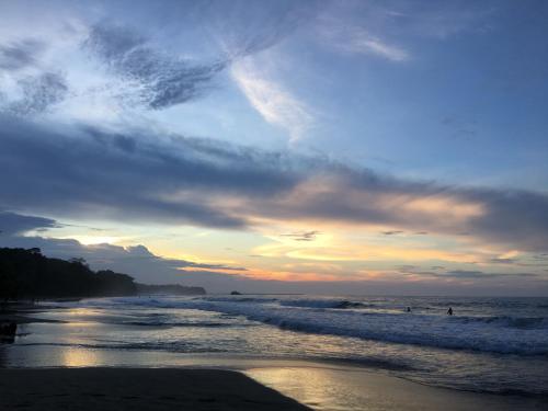 a sunset at the beach with people in the water at Le Cameleon Hotel in Puerto Viejo