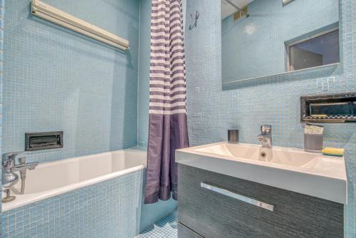 une salle de bain avec une baignoire, un lavabo et un miroir dans l'établissement Aquino, à Paris