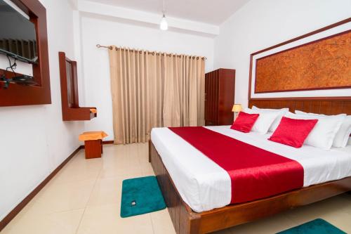 a bedroom with a large bed with red pillows at Colour Moon Hotel in Kotagala
