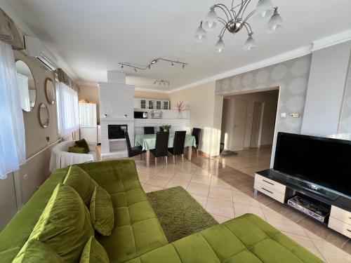 a living room with a green couch and a television at RELAX Apartman in Nyíregyháza