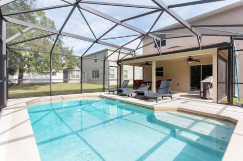 a large swimming pool with two chairs and a house at Clearwater Holiday Home in Clearwater