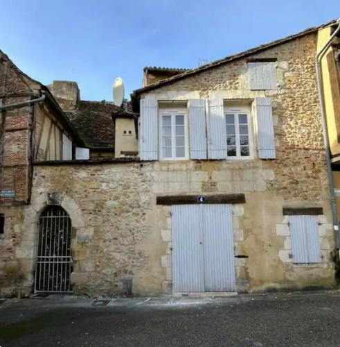 Cette ancienne maison en pierre est dotée de portes et de fenêtres blanches. dans l'établissement La maison des remparts, à Bergerac