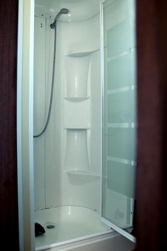 La salle de bains est pourvue d'une douche blanche avec une porte en verre. dans l'établissement mobil home v198, à Sigean