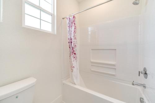 a white bathroom with a tub and a window at Pool Paradise Spacious Tracy Home with Yard! in Tracy
