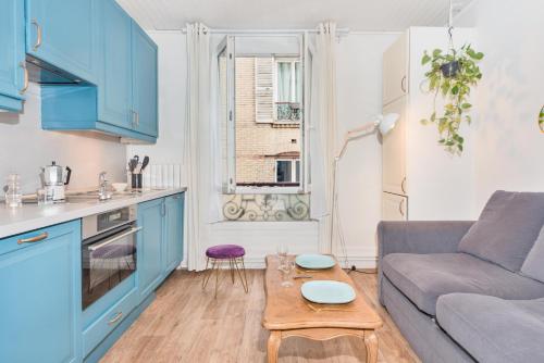 une cuisine avec des armoires bleues, un canapé et une table dans l'établissement Apartment for 6 persons in central Paris, à Paris