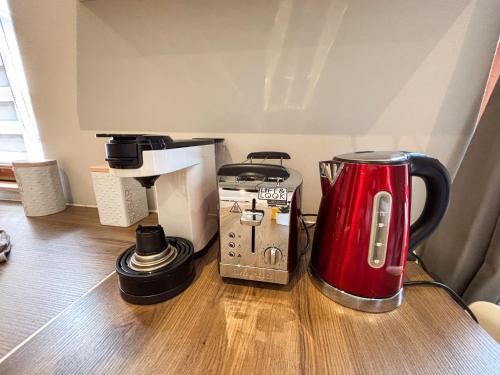 a red appliance sitting on top of a wooden table at Le Pavillon des Remparts - Commerces à proximité - Centre-ville - Appartement Cosy in Obernai
