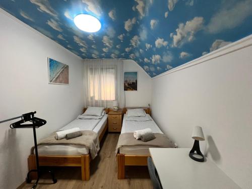 dwa łóżka w pokoju z sufitem w chmurki w obiekcie RELAX Apartman w Nyíregyházie