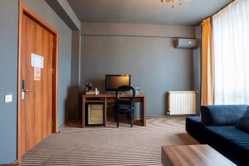 a living room with a couch and a desk with a television at Alex&George Boutique Hotel in Cluj-Napoca