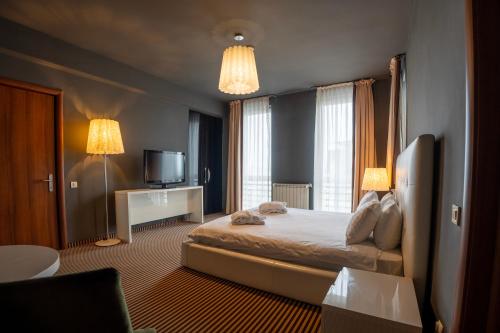 a hotel room with a bed and a television at Alex&George Boutique Hotel in Cluj-Napoca