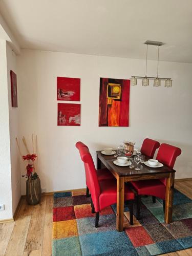a dining room with a table and red chairs at Bambus in Wangerland