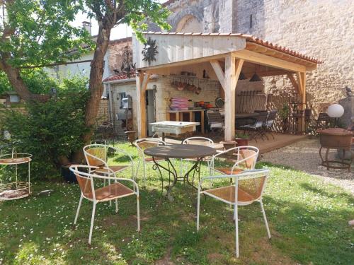 a picnic table and chairs in a backyard with a pavilion at le vieux prieure in Cressé