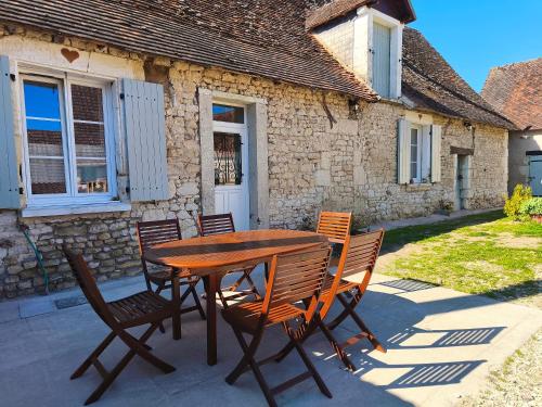 a wooden table and chairs in front of a house at Gîte Chez Renée in Azay-le-Ferron