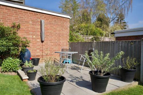 a patio with potted plants and a table and a fence at Natures Lodge Fully Furnished Home Coventry in Coventry