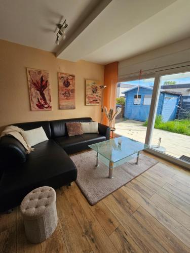 a living room with a black couch and a glass table at Bambus in Wangerland