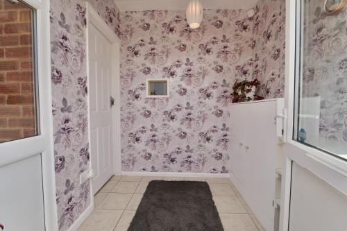 a small hallway with pink floral wallpaper at Natures Lodge Fully Furnished Home Coventry in Coventry