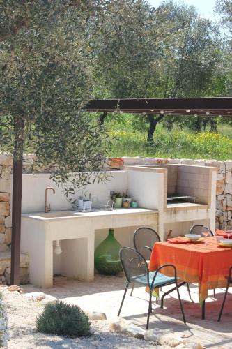 a outdoor kitchen with a table and a table and chairs at Trulli di Titti - Luxury Country House in Castellana Grotte