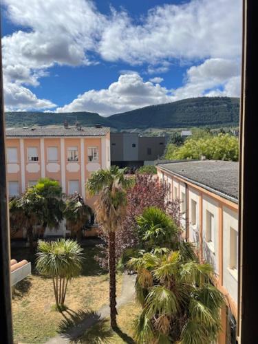 - une vue sur un bâtiment et des palmiers depuis une fenêtre dans l'établissement T1 Calme Ajouré et Traversant proche Centre ville, à Millau